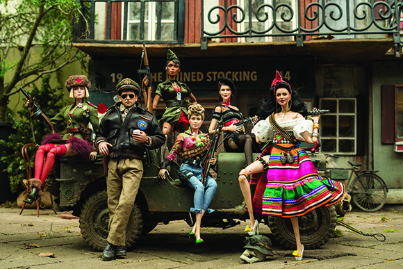 Fashion dolls in various outfits posed around a miniature olive green military jeep.