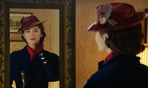 A woman wearing a red hat and dark coat looks at her reflection in a mirror.