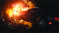 A dark car engulfed in bright orange flames and sparks during an explosion at night.