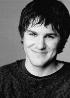 Black and white headshot of a young man with dark hair smiling at the camera.