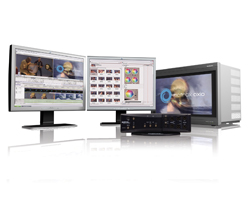 Two computer monitors displaying editing software next to a black hardware unit and a large monitor system.