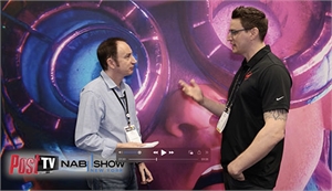 Two men in collared shirts converse in front of a large purple and blue circular graphic.