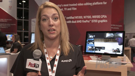 A woman wearing a black AMD polo shirt and a lanyard speaks while holding a microphone.