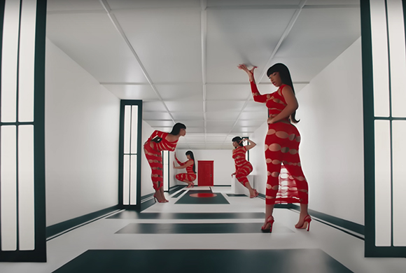 Three women in red patterned outfits pose in a minimalist white hallway with black accents.