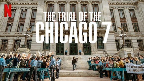 The Trial of the Chicago 7 title over a large building with a crowd and police officers in front.