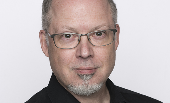 A man with short hair, glasses, and a small grey goatee looking directly at the camera.