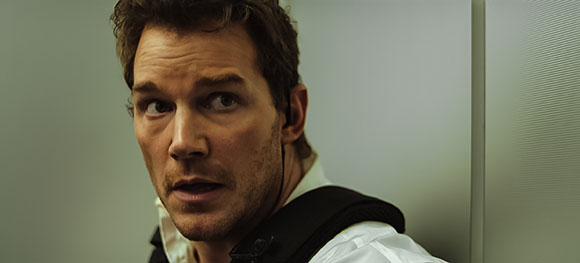 A man with brown hair and a startled expression looks off-camera against a neutral background.