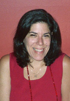 A smiling woman with dark hair wearing a red sleeveless top and a necklace.