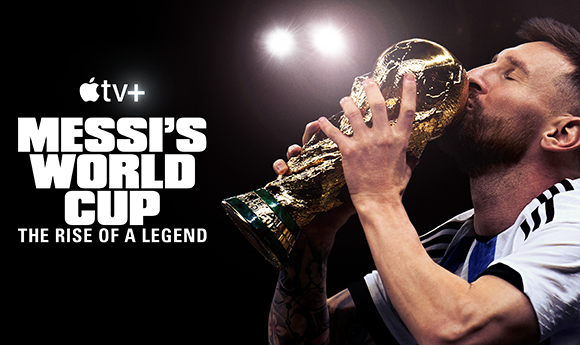 A soccer player kisses the gold World Cup trophy against a dark background.