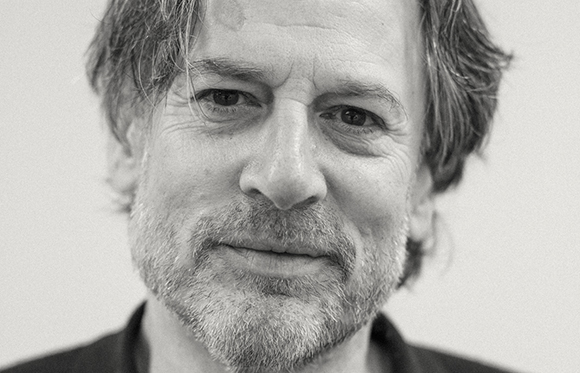 Close-up black and white portrait of a man with light-colored hair and a salt-and-pepper beard.