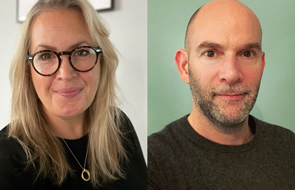 A blonde woman in glasses and a bald man with a beard looking at the camera.