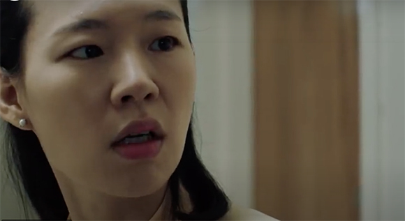 Close-up of a woman looking to the side with a worried or surprised facial expression.