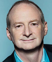 A man with light skin and thinning hair looking forward against a solid blue background.
