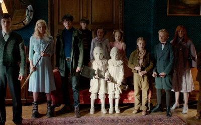 A group of diverse young people standing in a line in a dark, vintage-style room.