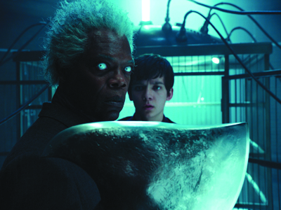 A man with white hair and glowing eyes stares intensely next to a younger man in a blue-lit room.