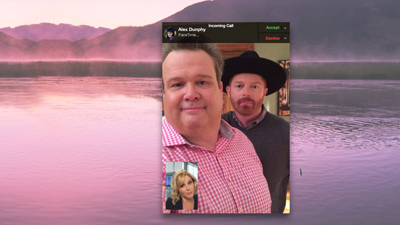 A FaceTime call showing two men in the foreground over a pink-hued misty lake and mountains.
