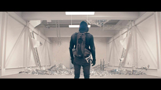 A person seen from behind standing in a room filled with scattered white debris and broken fragments.