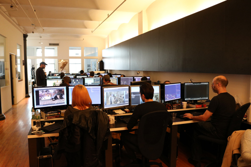 People working on computers in a modern office with multiple monitors and desks.