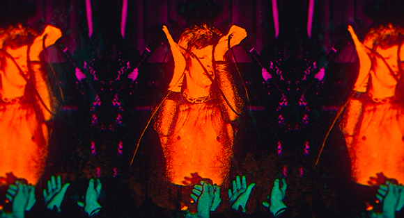 A mirrored, high-contrast projection of a person in glowing orange against a dark, patterned background.