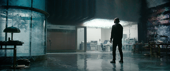 A silhouette of a person standing in a dark, cavernous room looking toward a bright overhead light.