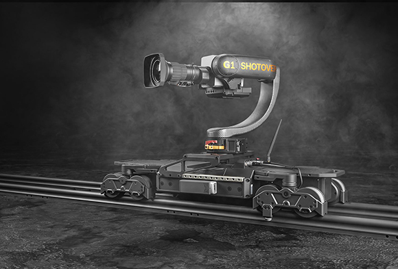 A large professional camera mounted on a curved robotic arm atop a motorized trolley on metal tracks.