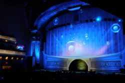 A theater stage glowing with bright blue light and large circular projections.