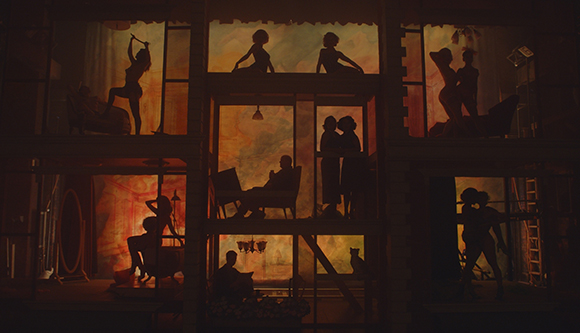 Silhouettes of people in various poses within a multi-story, room-like structure against a glowing orange sky.