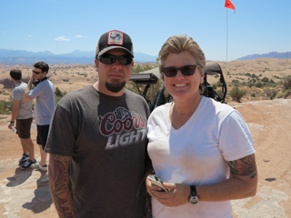 A man in a Coors Light t-shirt and a woman in a white t-shirt smile for a photo in a desert setting.