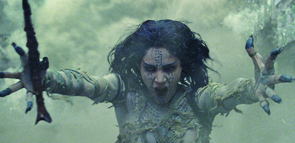 A pale woman with dark hair reaches toward the camera with clawed hands in a misty setting.