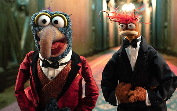Two Muppet puppets wearing tuxedos standing in a dimly lit hallway.