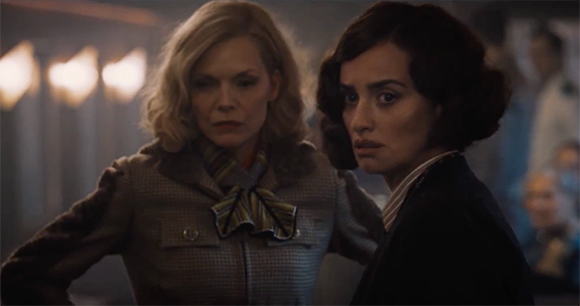 Two women with serious expressions looking toward the side in a dimly lit setting.