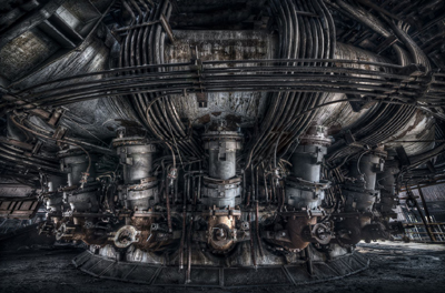 A wide view of heavy industrial machinery with numerous interconnected metal pipes and large cylindrical components.