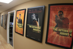 Three framed movie posters titled "The Return of Johnny V." hanging on a beige hallway wall.