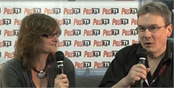 A woman and a man hold microphones while speaking in front of a repeating Post TV logo background.