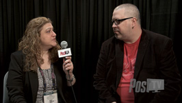 A woman holds a microphone toward a man wearing glasses and a red shirt during an interview.