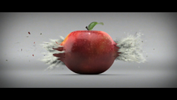 A red apple sits on a gray surface with white powder exploding from its sides.