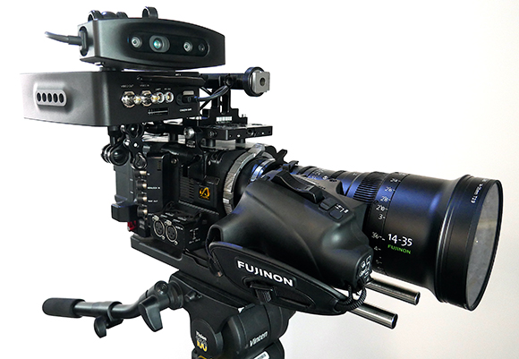 A professional black video camera with a large lens and top-mounted accessories mounted on a tripod.
