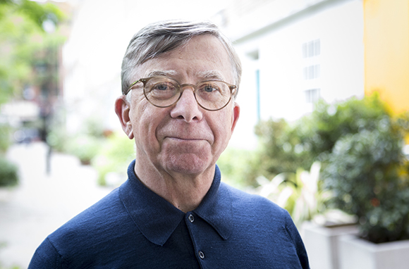 A man with short brown hair and glasses wearing a dark blue polo shirt, looking at the camera.