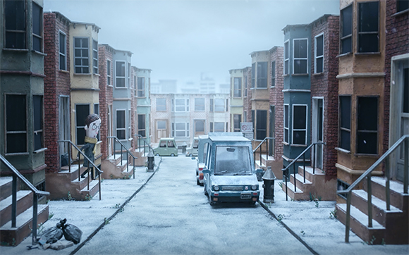 A stop-motion animation scene of a street lined with houses and parked cars covered in snow. A character walks down the steps