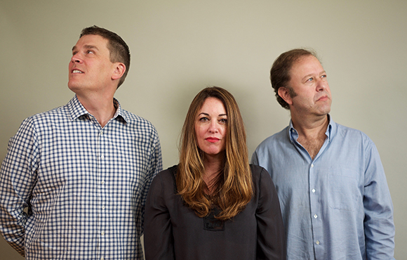 A man in a checkered shirt looks up, a woman looks forward, and a man in a blue shirt looks to the side.