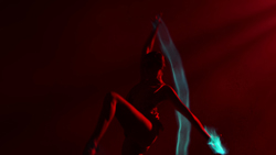 Silhouette of a person dancing with flowing blue light trails against a deep red background.