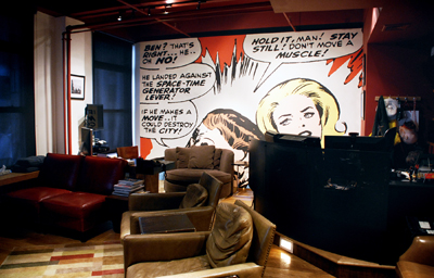 A large comic book style mural on a wall behind leather armchairs and a dark counter.