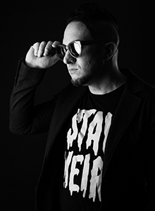 Black and white portrait of a man wearing sunglasses and a jacket over a graphic t-shirt.