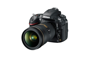 A black Nikon DSLR camera with a large professional lens positioned against a white background.