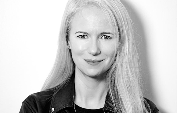 Black and white portrait of a woman with long blonde hair looking directly at the camera.