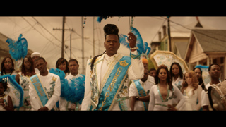 A group of people wearing elaborate blue and white ceremonial costumes standing outdoors in a residential area.
