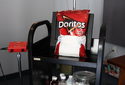 A bag of Doritos Nacho Cheese chips placed on top of a white diaper on a black utility cart.