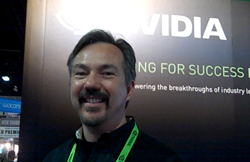 A smiling man with a mustache and goatee standing in front of a large NVIDIA banner.