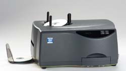 A grey electronic device with a white disc being placed into a slot on top.
