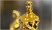 A gold Academy Award statuette standing against a blurred background.